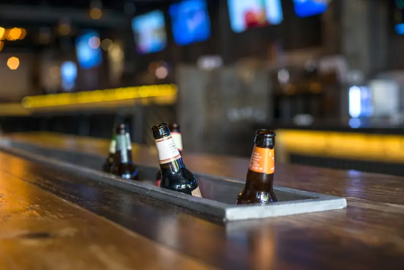 Bottles lined up along the bar rail at Wayward